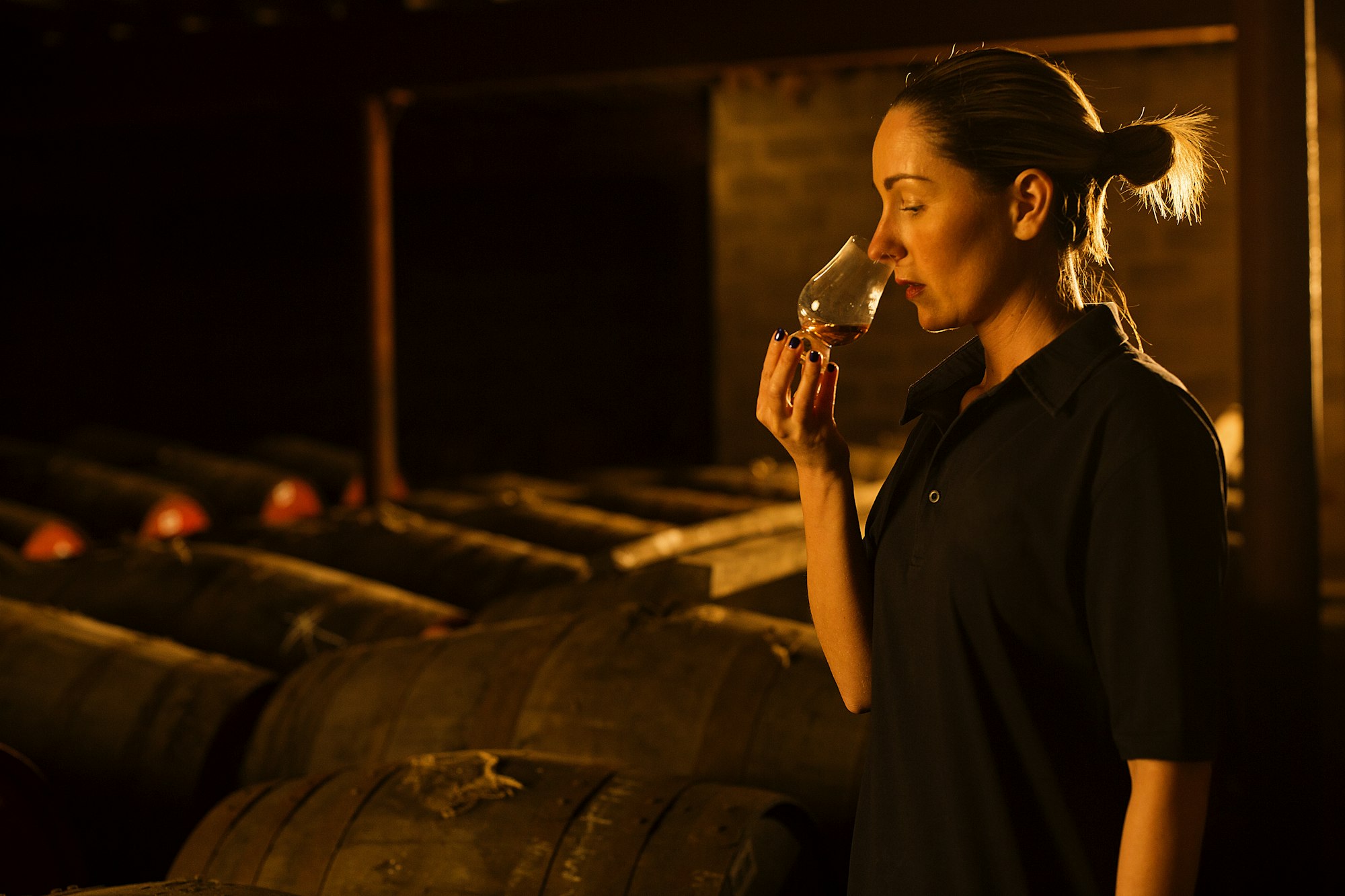 Female taster smelling whisky in glass at whisky distillery